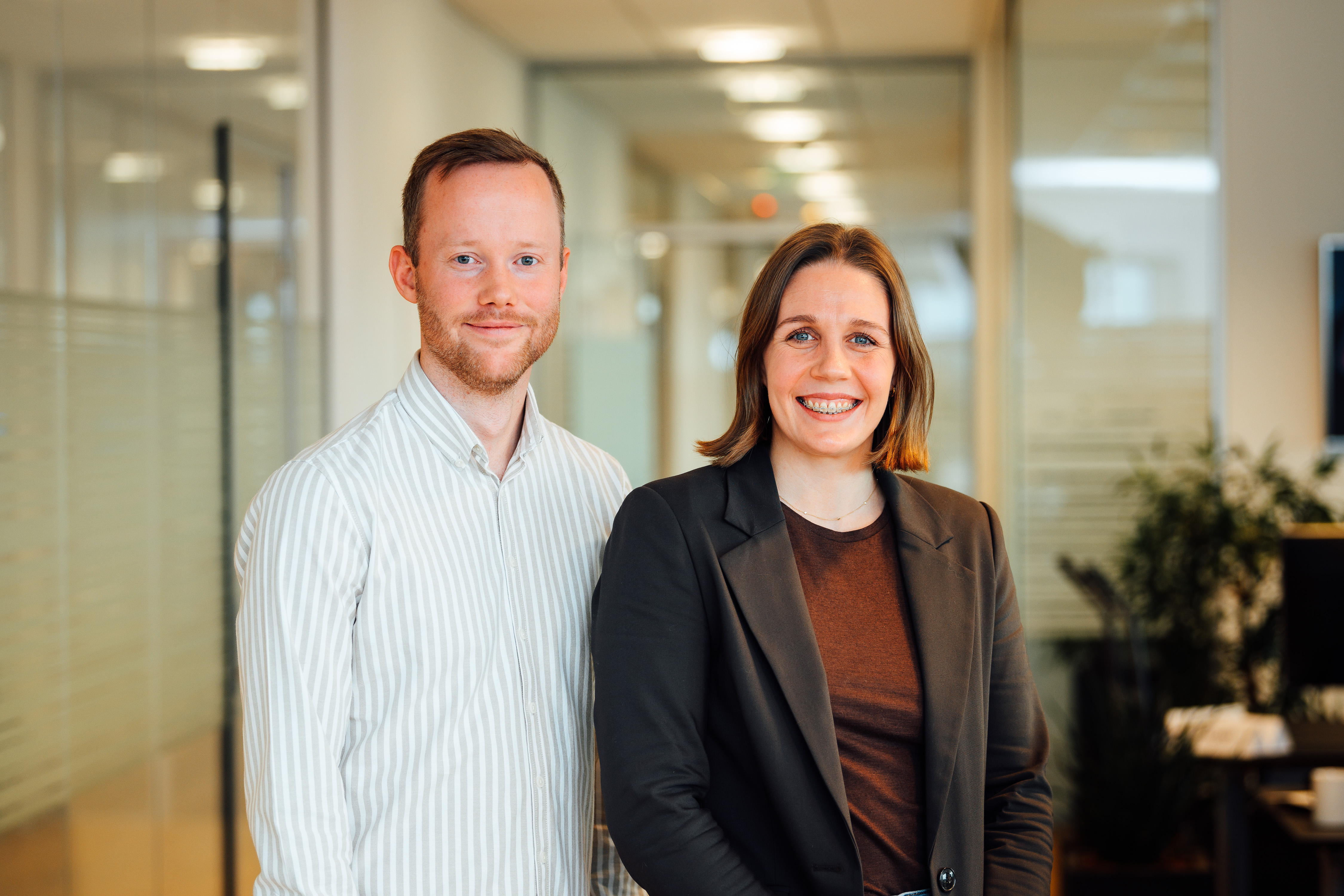 Smiling support representative wearing a headset, working on a laptop at a desk in a well-lit office