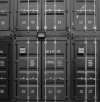 Stacked black cargo containers with identification markings, featuring a utilitarian design