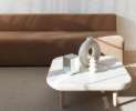 Stilvoller Wohnbereich mit braunem Sofa, weißem Marmortisch und minimalistischer Dekoration im natürlichen Licht.
