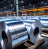 Rows of large, shiny metal coils neatly arranged in a spacious industrial warehouse."